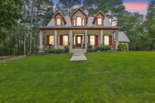 view of front of house with covered porch, metal roof, and a front yard