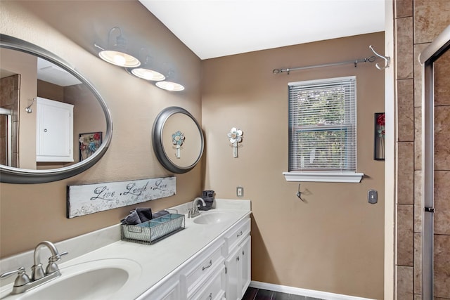 bathroom featuring a sink, a tile shower, and double vanity