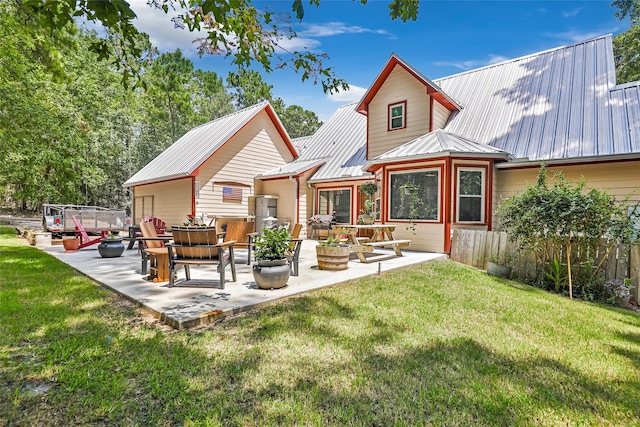 rear view of property featuring a patio, a yard, and metal roof