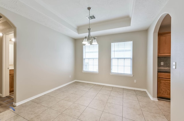 unfurnished dining area featuring visible vents, light tile patterned flooring, baseboards, a tray ceiling, and arched walkways