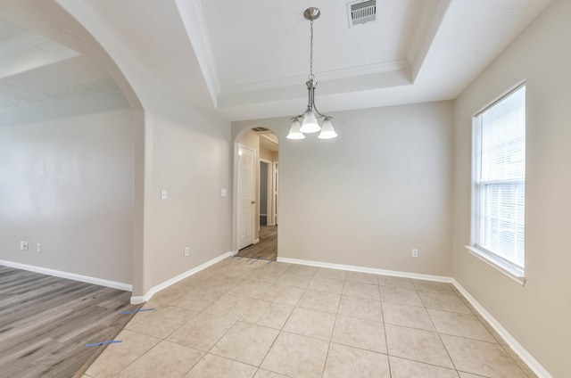 spare room featuring visible vents, arched walkways, a raised ceiling, and crown molding