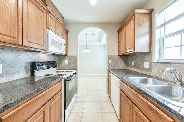 kitchen with dark countertops, arched walkways, a sink, baseboards, and white appliances