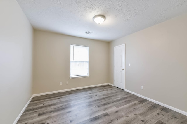 unfurnished room featuring a textured ceiling, baseboards, and wood finished floors