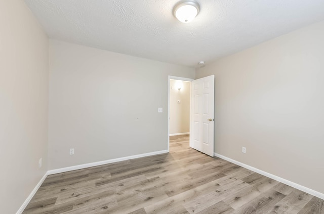 unfurnished room featuring baseboards, a textured ceiling, and wood finished floors