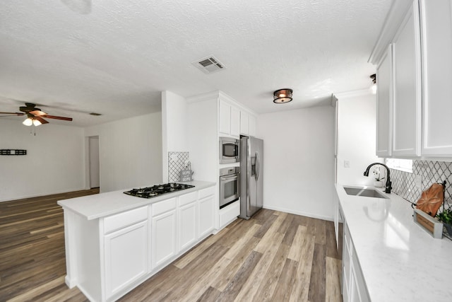 kitchen with visible vents, appliances with stainless steel finishes, tasteful backsplash, a sink, and light countertops