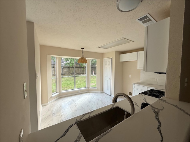 16319 Chimneystone Dr, Houston, TX 77095 - kitchen featuring white cabinetry, a textured ceiling, tasteful backsplash, a sink, and pendant lighting