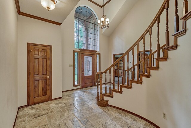 entryway with baseboards, a high ceiling, stone tile floors, stairway, and a chandelier