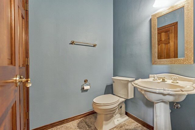 half bathroom featuring baseboards and toilet