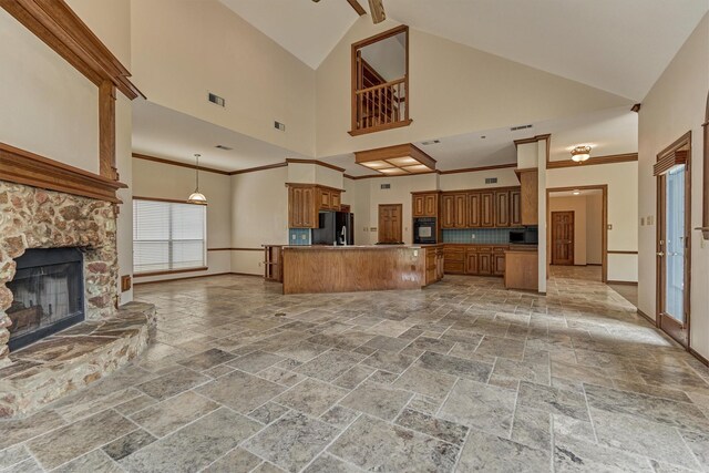 kitchen featuring open floor plan, stone tile floors, black appliances, brown cabinets, and a fireplace