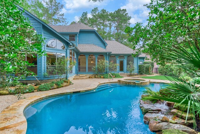 view of pool featuring a pool with connected hot tub, a patio, and a sunroom
