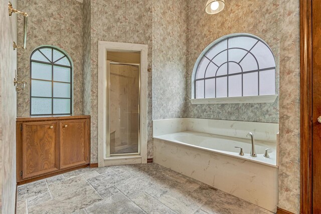 full bathroom with a stall shower, a garden tub, and stone finish flooring