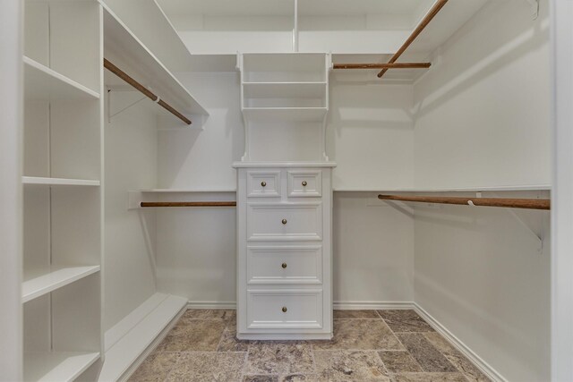 walk in closet with light stone finish flooring