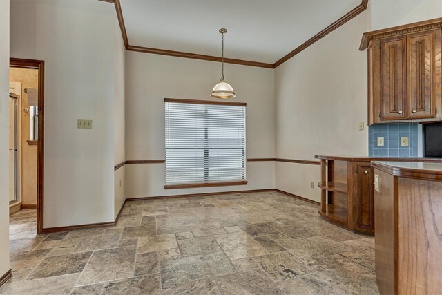 kitchen featuring stone tile flooring, baseboards, ornamental molding, brown cabinets, and hanging light fixtures