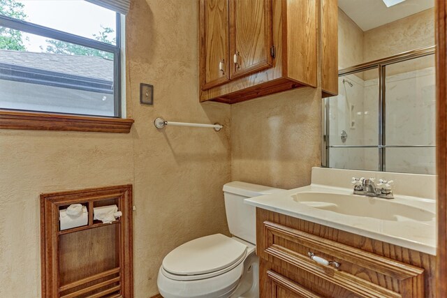 bathroom with a textured wall, a stall shower, toilet, and vanity