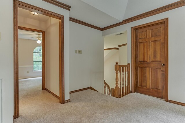 corridor with an upstairs landing, light colored carpet, baseboards, and ornamental molding