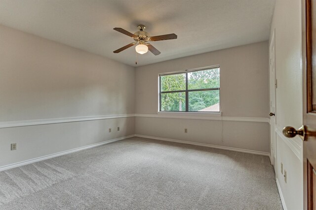 carpeted empty room featuring ceiling fan and baseboards