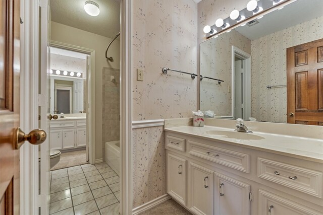 bathroom with toilet, tile patterned floors, wallpapered walls,  shower combination, and vanity