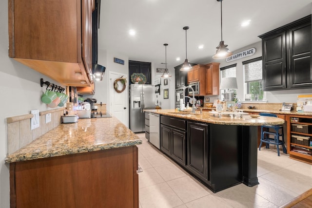 kitchen with a sink, dark cabinetry, stainless steel appliances, and an island with sink