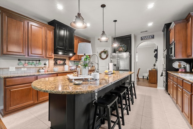 kitchen with stainless steel appliances, arched walkways, visible vents, and light tile patterned floors