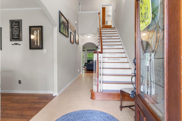 interior space with crown molding, arched walkways, baseboards, and tile patterned flooring