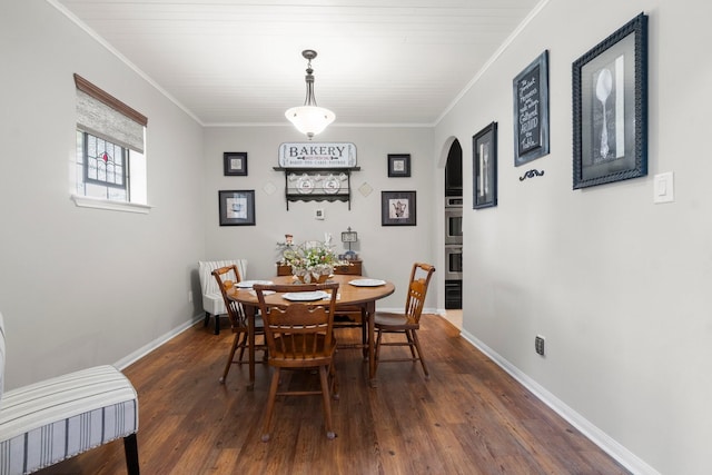 dining room with arched walkways, ornamental molding, baseboards, and wood finished floors