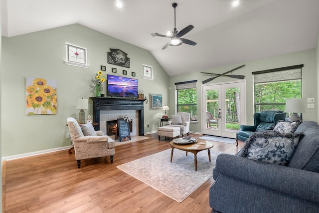 living area with a fireplace, light wood-style floors, baseboards, ceiling fan, and high vaulted ceiling
