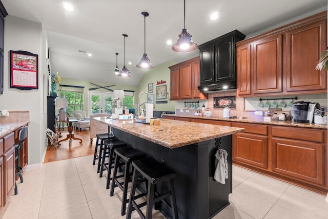 kitchen featuring decorative light fixtures, light stone counters, recessed lighting, light tile patterned flooring, and an island with sink