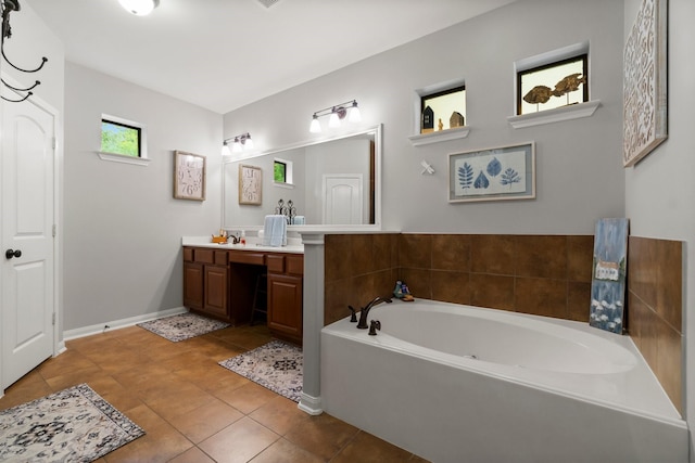 bathroom with baseboards, tile patterned flooring, a bath, and vanity