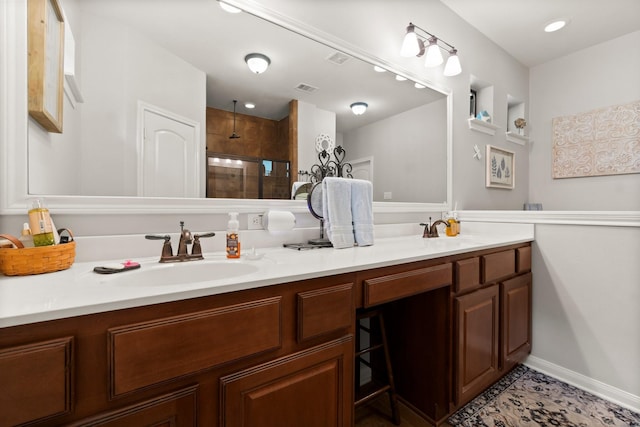 bathroom featuring double vanity, a sink, and tiled shower