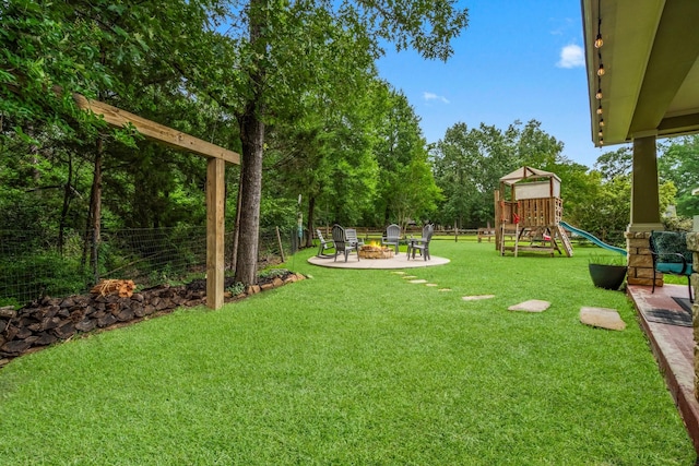 view of yard featuring fence, a playground, and an outdoor fire pit