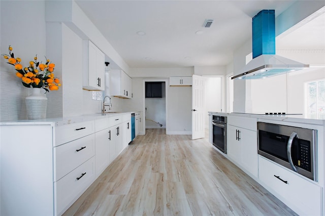1719 Wagon Gap Trl, Houston, TX 77090 - kitchen with stainless steel appliances, island exhaust hood, a sink, white cabinets, and light wood-type flooring