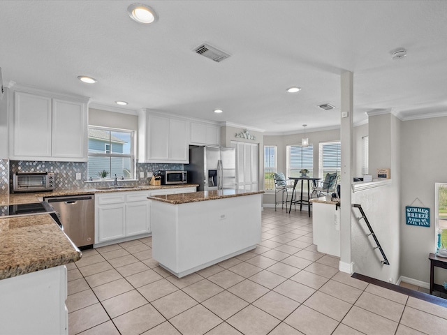 4035 Estuary Ct, Galveston, TX 77554 - kitchen featuring stainless steel appliances, a sink, a center island, decorative backsplash, and healthy amount of natural light