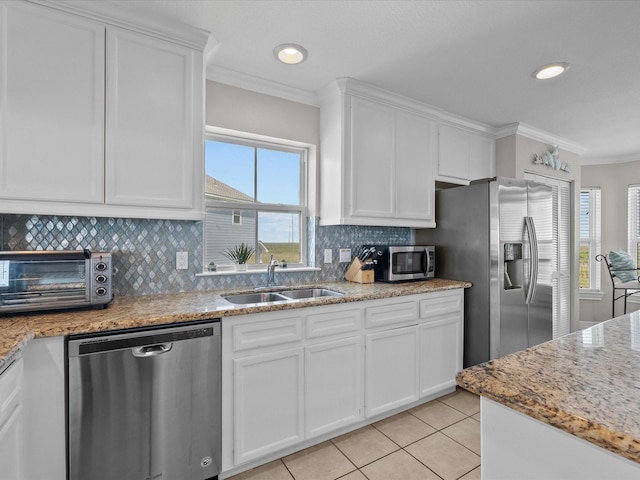 4035 Estuary Ct, Galveston, TX 77554 - kitchen featuring appliances with stainless steel finishes, a sink, ornamental molding, light tile patterned floors, and white cabinets