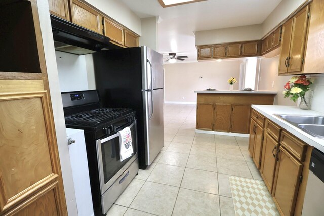 1217 E Brown Ln, Deer Park, TX 77536 - kitchen with gas range, brown cabinets, under cabinet range hood, a sink, and light countertops