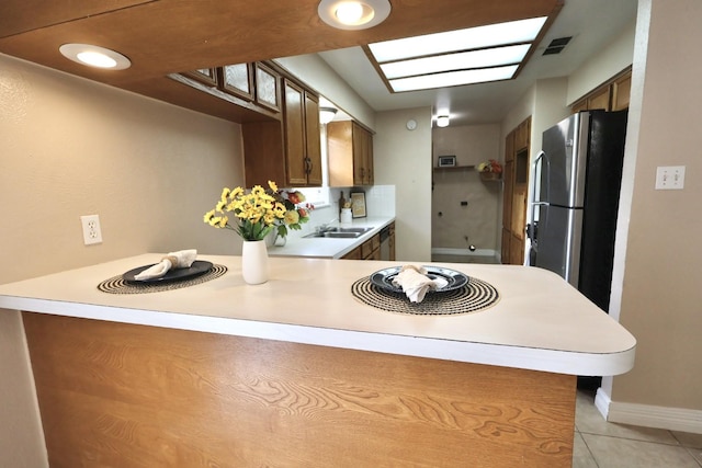 1217 E Brown Ln, Deer Park, TX 77536 - kitchen featuring stainless steel appliances, light tile patterned floors, a sink, light countertops, and a peninsula