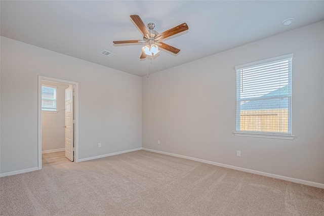 empty room featuring visible vents, a ceiling fan, baseboards, and light carpet