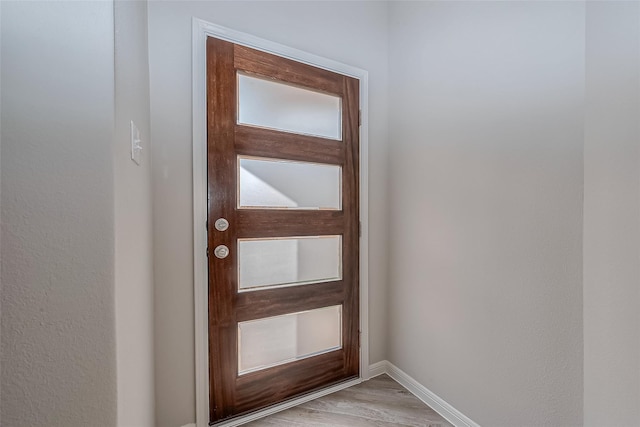 doorway with baseboards and light wood-type flooring