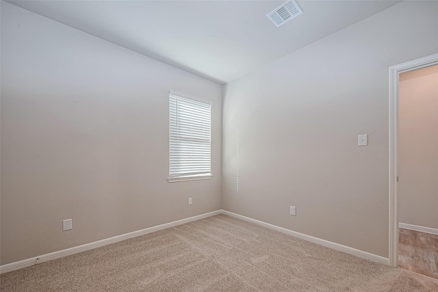 spare room with visible vents, baseboards, and light colored carpet
