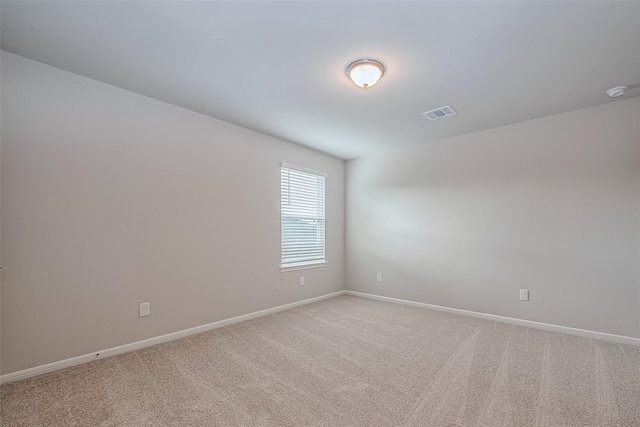 empty room featuring baseboards, visible vents, and light carpet