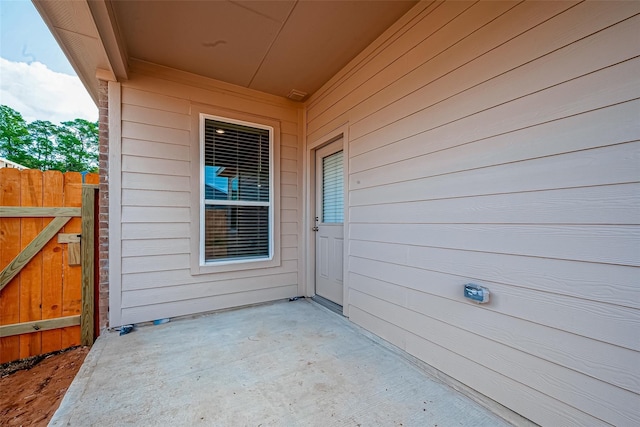 view of exterior entry featuring a patio and fence
