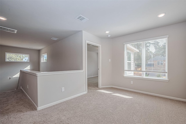 empty room with carpet floors, baseboards, visible vents, and a healthy amount of sunlight