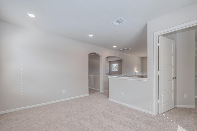 empty room featuring arched walkways, baseboards, carpet floors, and visible vents