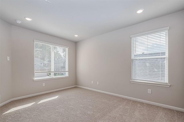 spare room featuring baseboards, light carpet, and recessed lighting