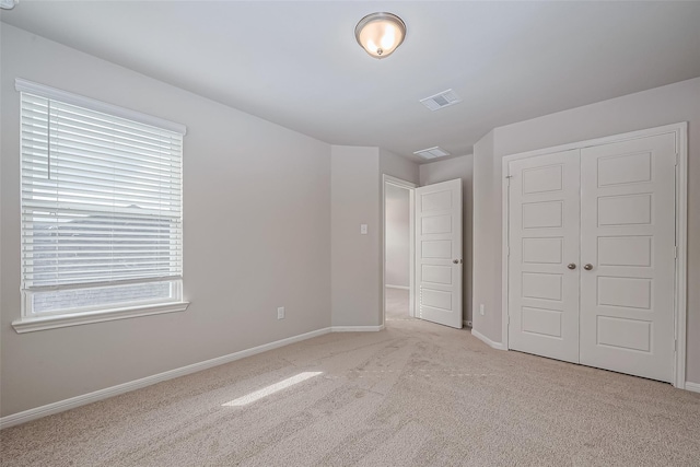 unfurnished bedroom featuring carpet flooring, baseboards, multiple windows, and a closet