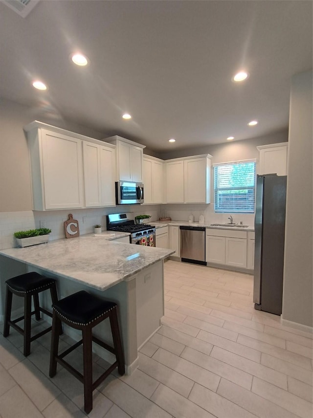 12303 Sterling Oak Dr, Humble, TX 77044 - kitchen featuring stainless steel appliances, a peninsula, white cabinetry, decorative backsplash, and recessed lighting