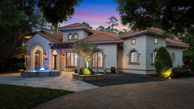 mediterranean / spanish-style home featuring a tile roof, a patio area, and stucco siding