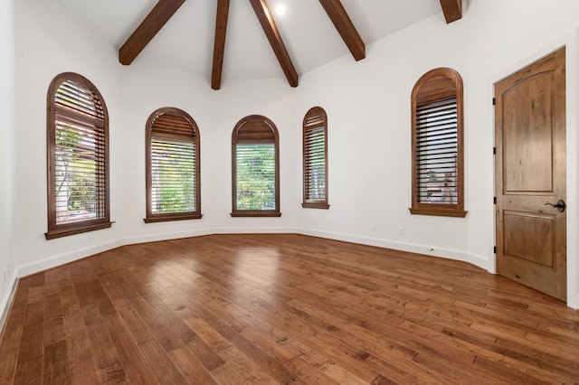 empty room featuring vaulted ceiling with beams, baseboards, and wood finished floors
