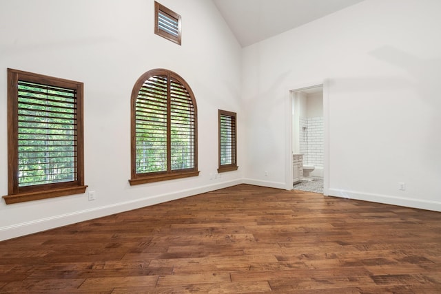 spare room featuring baseboards, high vaulted ceiling, and wood finished floors