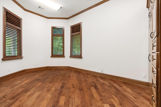empty room with visible vents, ornamental molding, baseboards, and wood finished floors