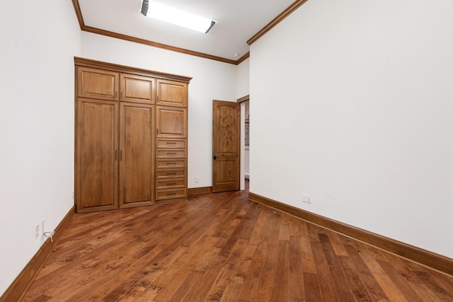 unfurnished bedroom with crown molding, baseboards, and dark wood-type flooring